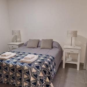 a bedroom with a bed with two tables and two lamps at Happy Guest Apart 53 in Ushuaia