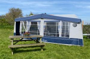 a blue and white tent with a wooden table at Caravan Weidezicht in Den Burg