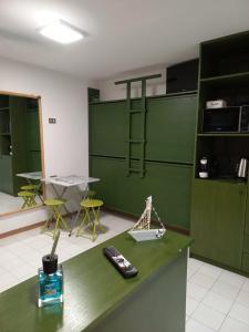 Cette chambre est dotée d'un mur vert avec télécommande sur un comptoir. dans l'établissement Monolocale a due minuti dal mare IUN R4225, à Marina di Portisco