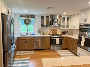 una cocina con armarios de madera y electrodomésticos de acero inoxidable en Modern Family Home in Middletown, RI- just 4 mi to Newport! en Middletown