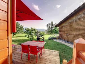 un patio con mesa, sillas y sombrilla en La Roulotte du Cagire - 4 pers - Pyrénées, en Villeneuve-de-Rivière