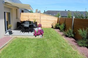 a backyard with a table and chairs and a fence at Baie du Mont Saint Michel / Gîte de la Vaquerie in Vains