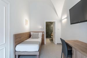 um pequeno quarto com uma cama e uma televisão em Dimora dei Celestini em Manfredonia