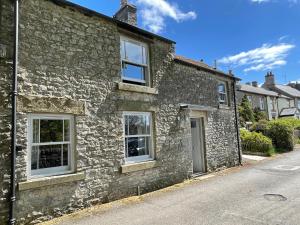 an old stone house with white windows on a street at Weavers Cottage, Tideswell, sleeps 6, dog friendly in Buxton