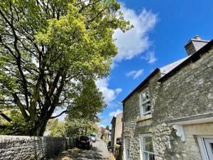 eine Straße in einem Dorf mit einem Steinhaus und einem Baum in der Unterkunft Weavers Cottage, Sleeps 6, outside terrace in Buxton
