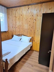 ein Schlafzimmer mit einem Bett mit einer Holzwand in der Unterkunft Комплекс Джулай Морнинг in Kiten