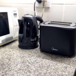 a black toaster sitting next to a microwave on a counter at Happy Guest Apart 53 in Ushuaia
