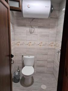 a bathroom with a toilet and a light on the wall at Комплекс Джулай Морнинг in Kiten