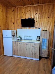 a kitchen with a white refrigerator and wooden walls at Комплекс Джулай Морнинг in Kiten