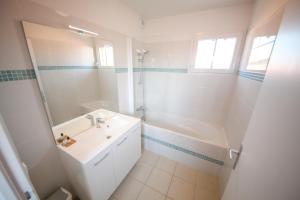 a white bathroom with a sink and a tub at Residence Plage Oceane in Biscarrosse-Plage