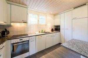 Una cocina con gabinetes blancos y un horno de estufa. en Les Chamois, en Arosa 19 fotos más
