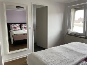1 dormitorio con espejo, cama y ventana en Altstadtperle Nideggen, en Nideggen