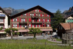 a large red building with people walking in front of it at Swiss Lodge Hotel Bernerhof in Wengen