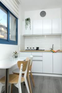 a kitchen with white cabinets and a table and chairs at Beach Suite Israel- True Beachfront Steps Away From Beach ביץ סוייט ישראל- במרחק צעדים מהים in Ashqelon