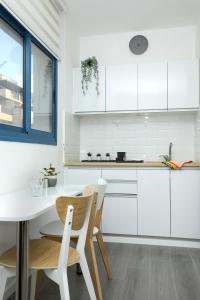 a kitchen with white cabinets and a table and chairs at Pool, Sauna, Gym & Spa @ Beach-Front Apartment Hotel in Ashkelon