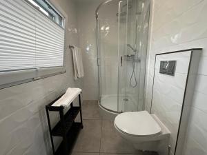 a white bathroom with a shower and a toilet at Sun House 
