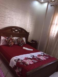 a bedroom with a bed with red sheets and pillows at Sweet Room Airport 5 in Deroua