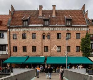 One World Hostel Gdansk في غدانسك: الناس يمشون أمام مبنى كبير من الطوب