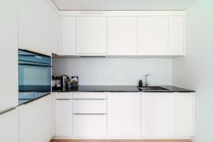 a white kitchen with white cabinets and a sink at Suite Parco Lago by Quokka 360 - Terraced flat close to Lido Locarno in Locarno