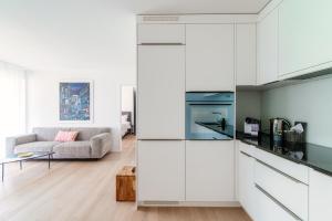 une cuisine avec des placards blancs et un salon dans l'établissement Suite Parco Lago by Quokka 360 - Terraced flat close to Lido Locarno, à Locarno