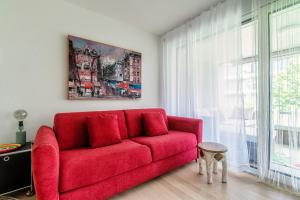 a red couch in a living room with a window at Suite Parco Lago by Quokka 360 - Terraced flat close to Lido Locarno in Locarno