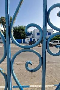 une porte bleue en métal avec un bâtiment en arrière-plan dans l'établissement La Maisonnette Turquoise, à Dar Mimoun Bey