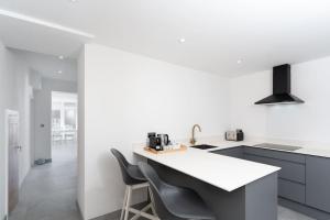 a kitchen with a white counter and two chairs at Stunning new 1 bed apartment in Marazion. in Marazion
