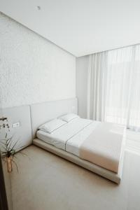 a white bedroom with a bed and a window at Villa Escape 21 in Durrës