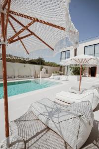 a pool with two beds and umbrellas next to a building at Villa Escape 21 in Durrës
