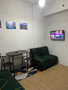 salon z kanapą, stołem i telewizorem w obiekcie Anuva Suite ( Free Swimming Access) w mieście Manila