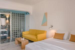 1 dormitorio con 1 cama y 1 silla amarilla en The Blue, en Skiathos