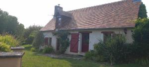 una pequeña casa blanca con puertas rojas en un patio en Gîte Les Toisnières, en Marigné-Laillé