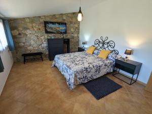 1 dormitorio con cama y pared de piedra en Can Carreres - Un lloc on desconnectar en família, en El Pasteral