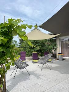 eine Gruppe Stühle und ein Sonnenschirm auf einer Terrasse in der Unterkunft The Private House in Siófok