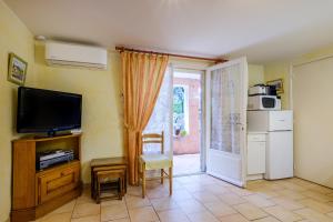 a living room with a television and a door to a patio at Ma Vie Là in Fayence