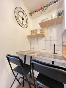 cocina con mesa y reloj en la pared en Le Toucan - Joli studio proche Tram & centre-ville, en Toulouse