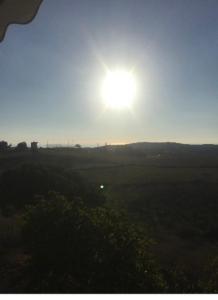 a sun setting over a field with the sun in the sky at Farmhouse in Volímai
