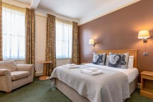 a hotel room with a bed and a chair at Swan Revived Hotel in Milton Keynes