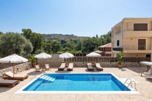 a pool with chairs and umbrellas next to a building at Adonis Villa in nature in Ixia