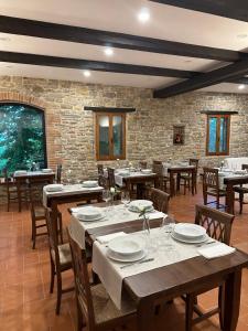 een restaurant met houten tafels en stoelen en een bakstenen muur bij Agriturismo Akasha in Branca