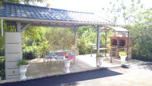 a pergola with a grill and a table and chairs at La Clef De Voute Amethyste in Saint-Genest
