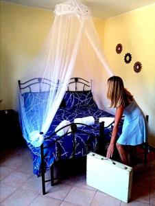 una joven parada junto a una cama con una maleta en Intera casa con due stanze nel Parco del Cilento, en Piaggine