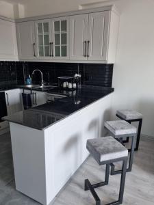 a kitchen with white cabinets and a sink and two stools at Uğur Apart Sea View in Erdemli