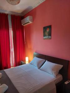 a bedroom with red walls and a bed with white sheets at ΠΙΘΟΣ ΕΝΟΙΚΙΑΖΟΜΕΝΗ ΚΑΤΟΙΚΙΑ in Kalamata