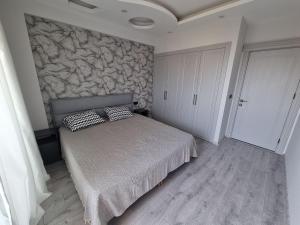 a bedroom with a bed and a stone wall at Uğur Apart Sea View in Erdemli