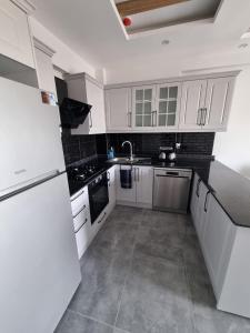 a kitchen with white cabinets and a white refrigerator at Uğur Apart Sea View in Erdemli