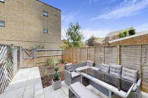 a patio with a couch and a fence at Modernistic 4 BR house with a garden in Islington in London