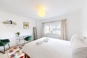 sypialnia z białym łóżkiem i 2 zielonymi krzesłami w obiekcie Modernistic 4 BR house with a garden in Islington w Londynie