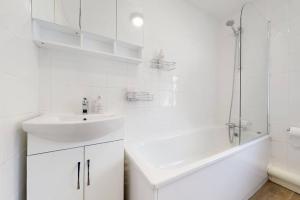 a white bathroom with a sink and a shower at Modernistic 4 BR house with a garden in Islington in London