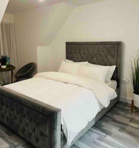 a bedroom with a large bed with white sheets at Luxurious new built kingsize bedroom in Manchester